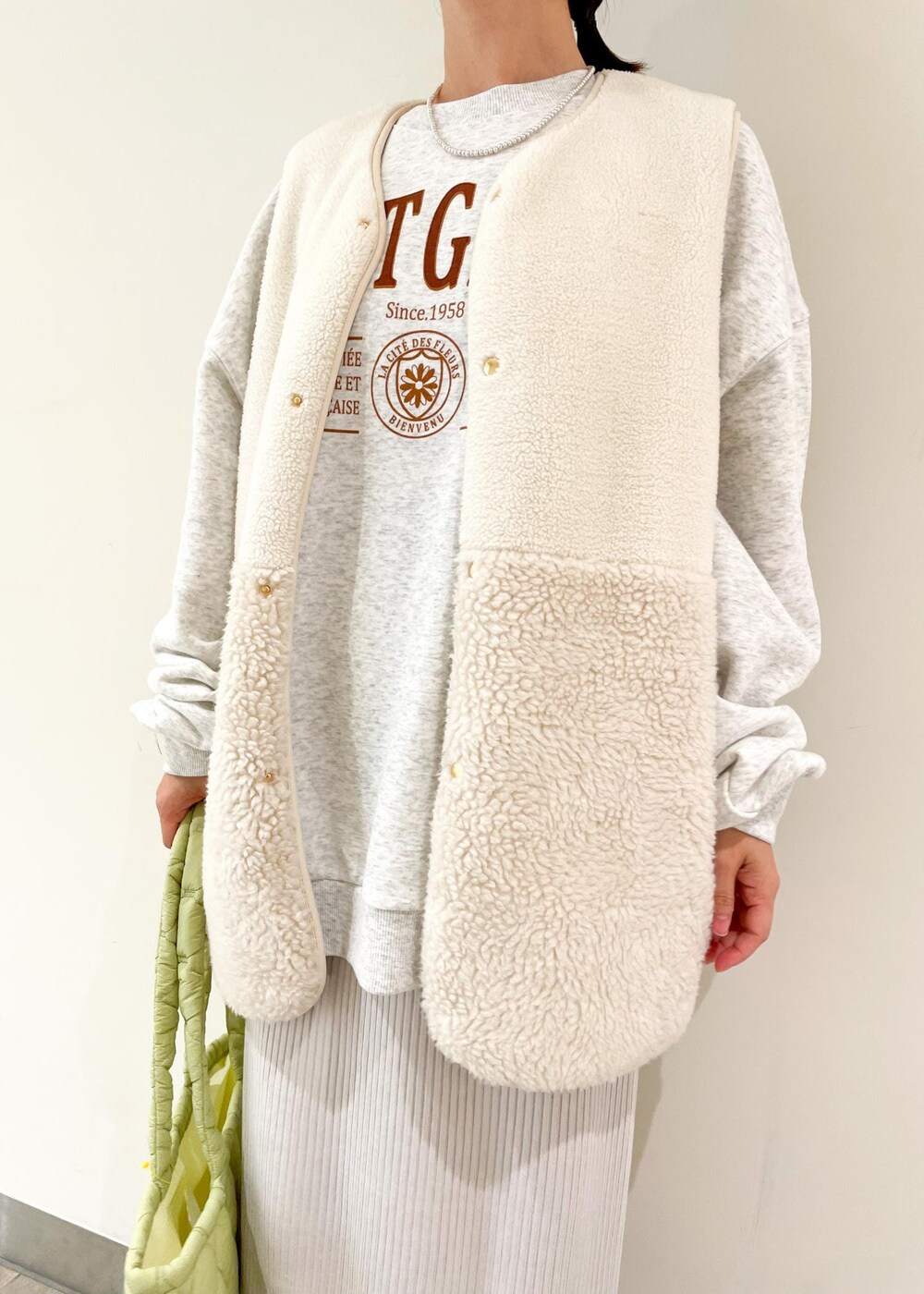 グレー系のスウェット、グレー系のスカート、グリーン系のトートバッグを着用したレディースの秋コーディネートの2枚目の写真