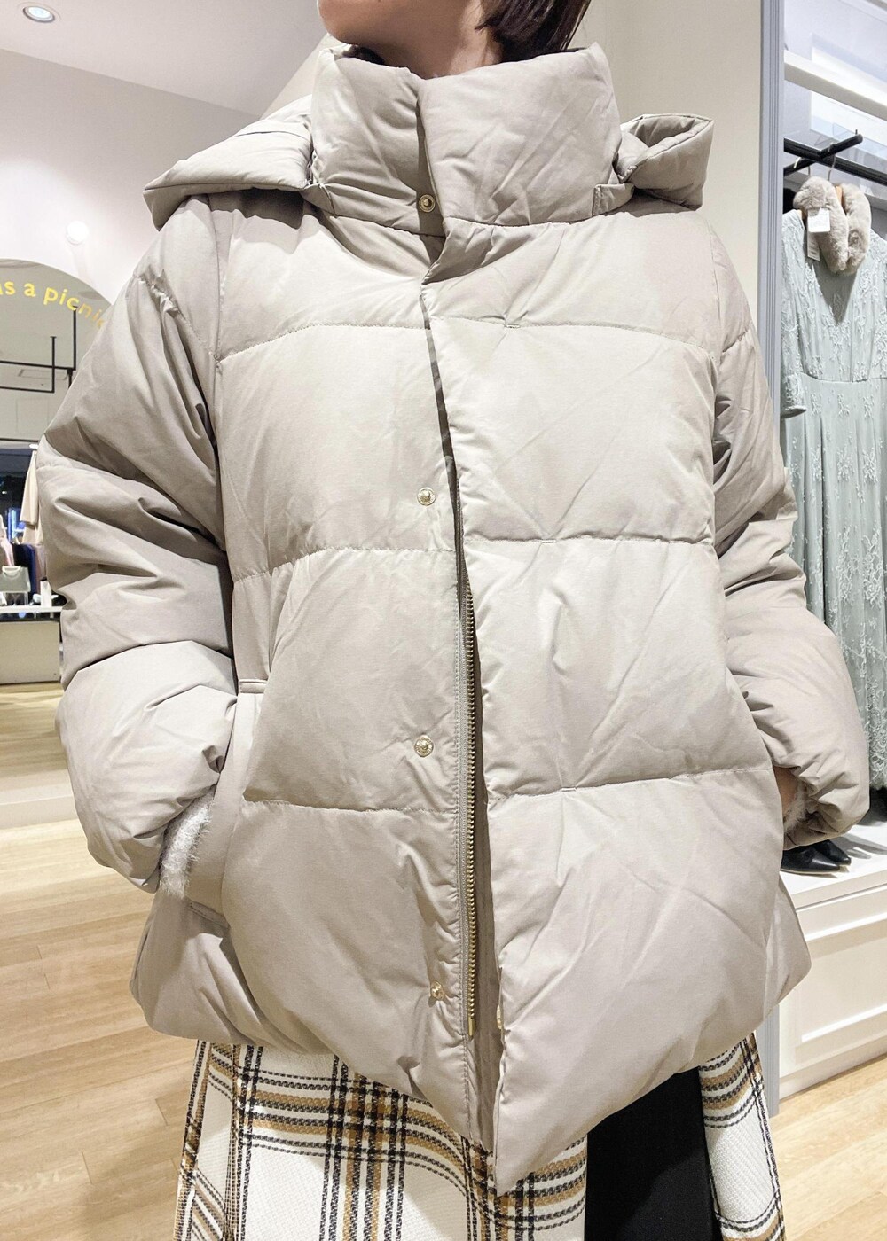 ブラウン系のダウンジャケット/コート、ブラック系のブーツ、ホワイト系のスカートを着用したレディースの冬コーディネートの3枚目の写真