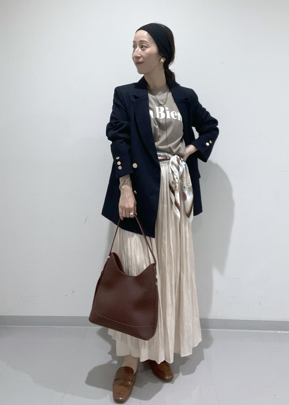 イエロー系のローファー、ベージュ系のスカート、レッド系のショルダーバッグを着用したレディースの夏コーディネートの4枚目の写真