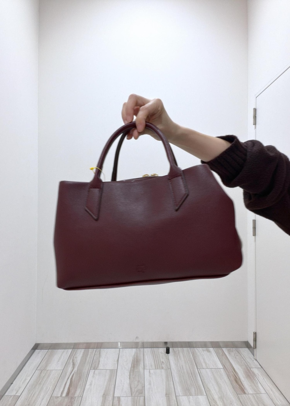 レッド系のトートバッグ、ブラック系のパンプス、ブラウン系のニット/セーターを着用したレディースの秋コーディネートの7枚目の写真