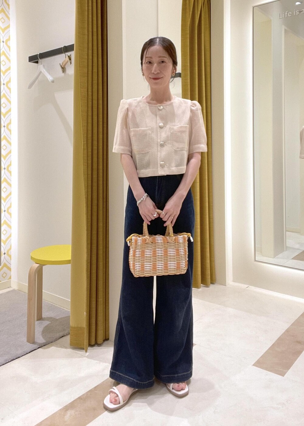 ブルー系のデニムパンツ、ホワイト系のサンダル、ベージュ系のかごバッグを着用したレディースの夏コーディネートの2枚目の写真