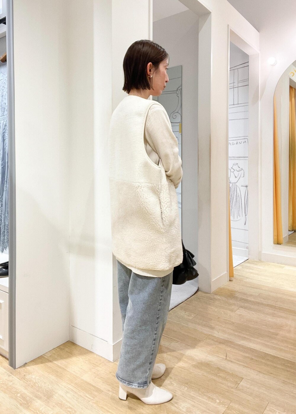 ブラック系のショルダーバッグ、ホワイト系のブーツ、ホワイト系のカーディガン/ボレロを着用したレディースの秋コーディネートの2枚目の写真