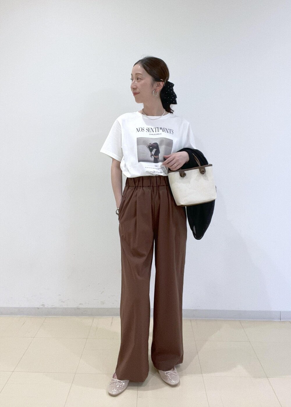 ブラック系のブルゾン、ホワイト系のバレエシューズ、ブラウン系のトートバッグを着用したレディースの春コーディネートの6枚目の写真