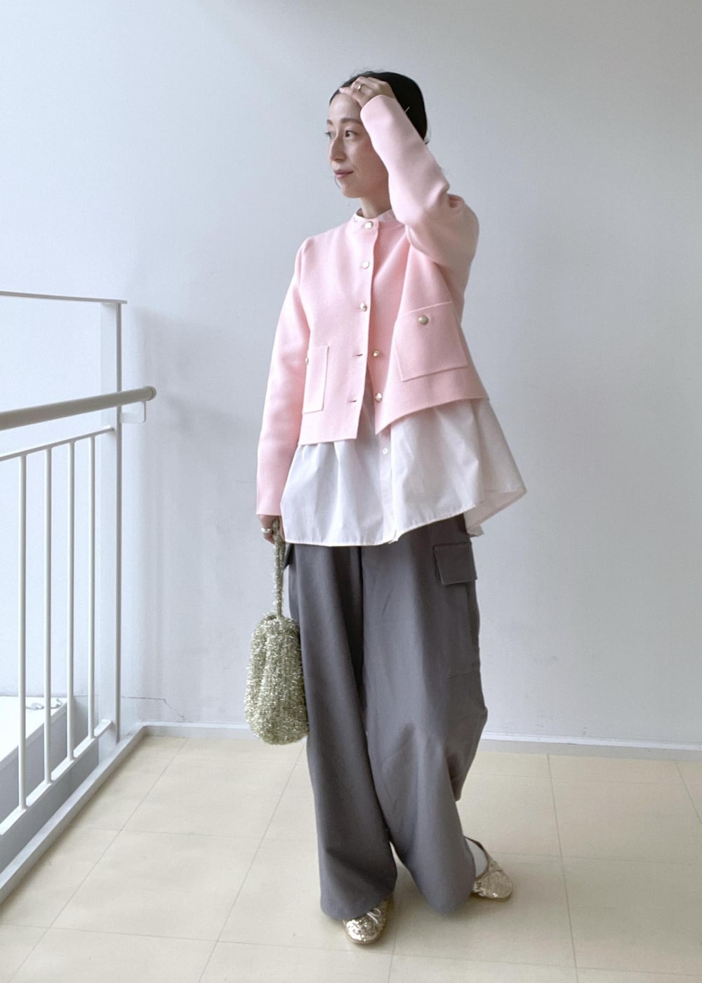 ゴールド系のショルダーバッグ、ブルー系のテーラードジャケット、ゴールド系のバレエシューズを着用したレディースの冬コーディネートの3枚目の写真