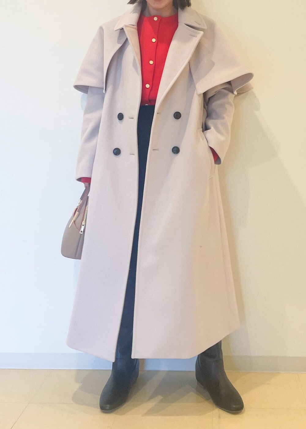 オレンジ系のカーディガン/ボレロ、ブラック系のスカート、ブラック系のブーツを着用したレディースの秋コーディネートの2枚目の写真