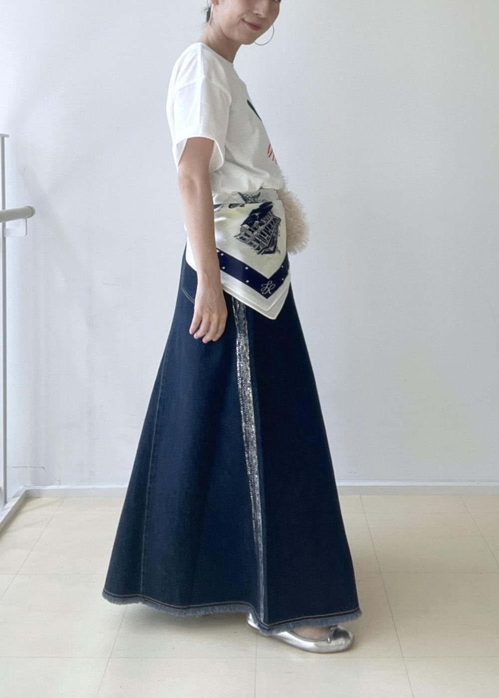 ホワイト系のTシャツ/カットソー、ベージュ系のハンドバッグ、ブルー系のデニムスカートを着用したレディースの夏コーディネートの3枚目の写真