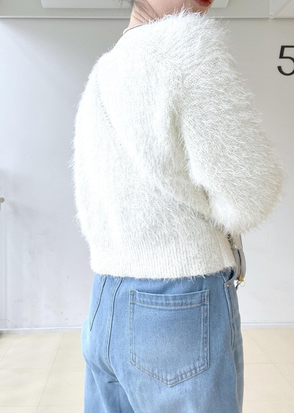 ホワイト系のニット/セーター、ホワイト系のTシャツ/カットソー、ブルー系のデニムパンツを着用したレディースの冬コーディネートの5枚目の写真