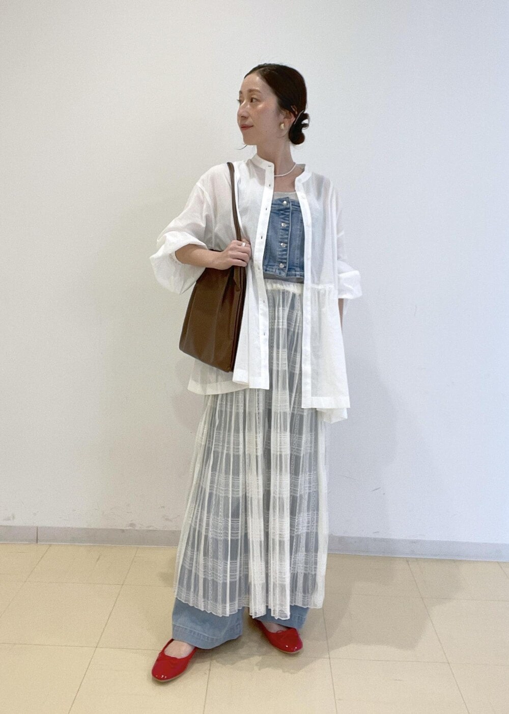 ホワイト系のスカート、ブルー系のベスト、ホワイト系のシャツ/ブラウスを着用したレディースの春コーディネートの2枚目の写真