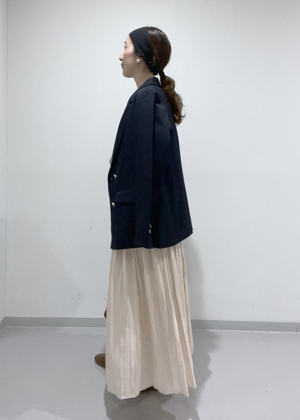 イエロー系のローファー、ベージュ系のスカート、レッド系のショルダーバッグを着用したレディースの夏コーディネートの3枚目の写真