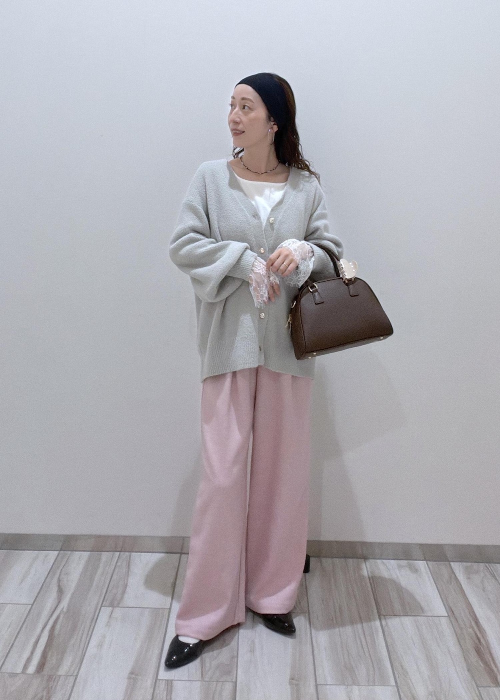 ピンク系のその他パンツ、グレー系のカーディガン/ボレロ、ブラウン系のボストンバッグを着用したレディースの秋コーディネートの2枚目の写真