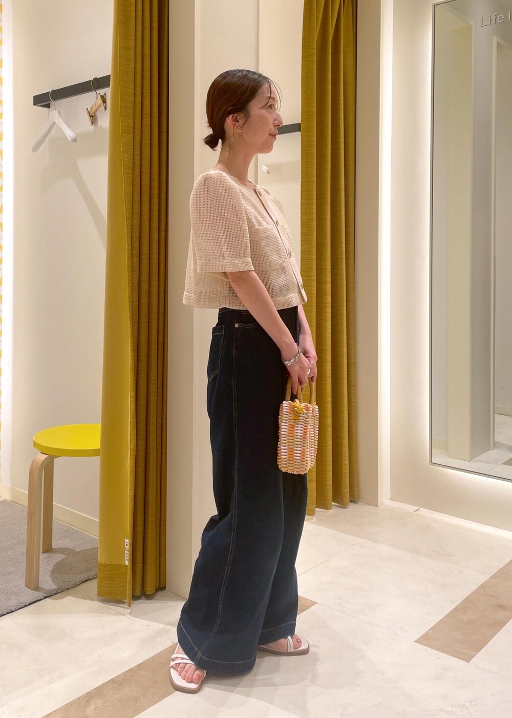 ブルー系のデニムパンツ、ホワイト系のサンダル、ベージュ系のかごバッグを着用したレディースの夏コーディネートの3枚目の写真