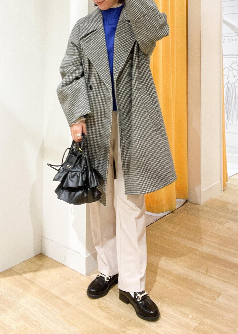 ブラック系のショルダーバッグ、ブルー系のニット/セーター、ブラック系のピーコートを着用したレディースの秋コーディネートの3枚目の写真