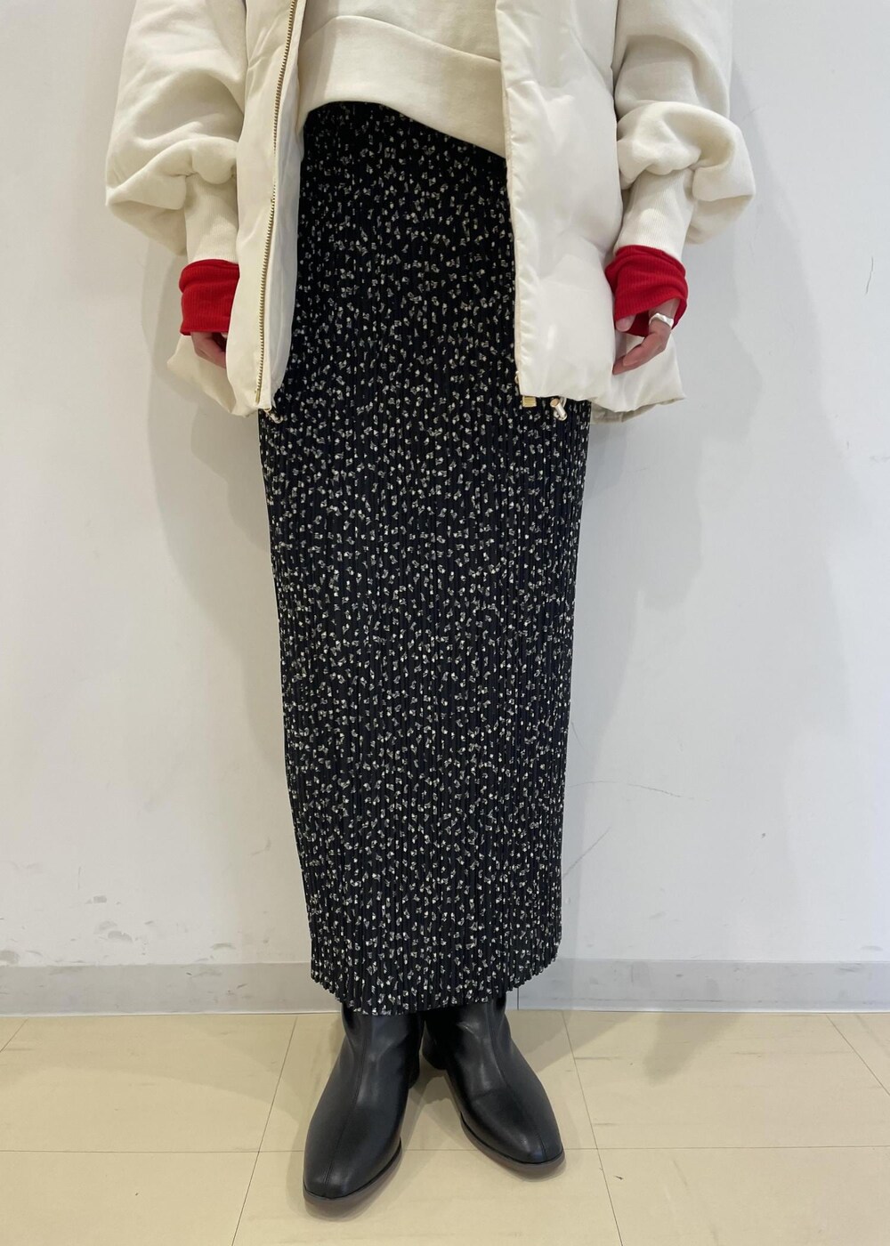 レッド系のTシャツ/カットソー、ブラック系のブーツ、ホワイト系のダウンベストを着用したレディースの冬コーディネートの3枚目の写真