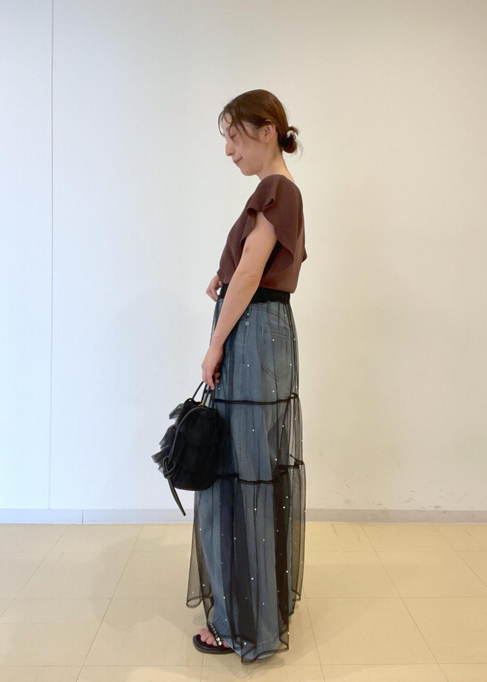 ブルー系のデニムパンツ、ブラック系のサンダル、ブラウン系のニット/セーターを着用したレディースの夏コーディネートの4枚目の写真