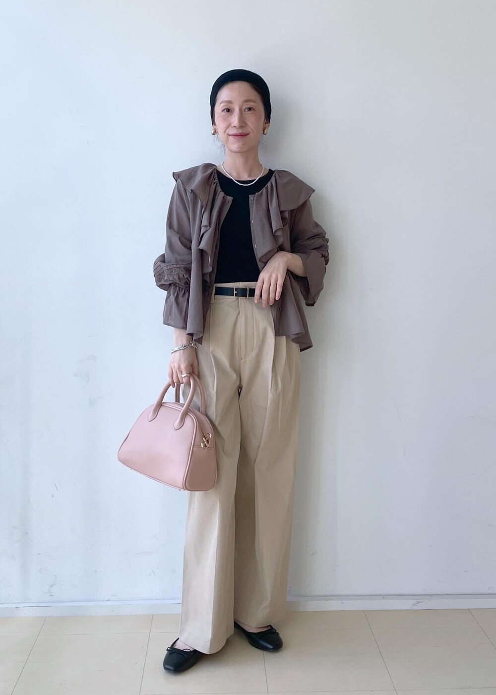 ベージュ系のチノパンツ、ピンク系のボストンバッグ、ブラック系のバレエシューズを着用したレディースの春コーディネートの2枚目の写真