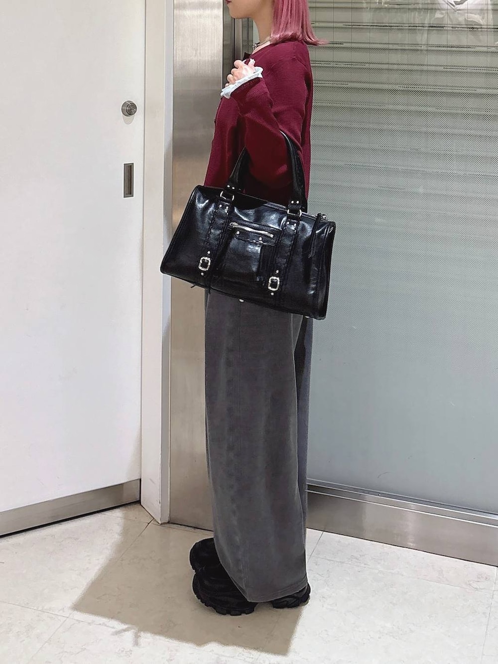 レッド系のカーディガン/ボレロ、ブラック系のローファー、ブラック系のボストンバッグを着用したレディースの秋コーディネートの2枚目の写真