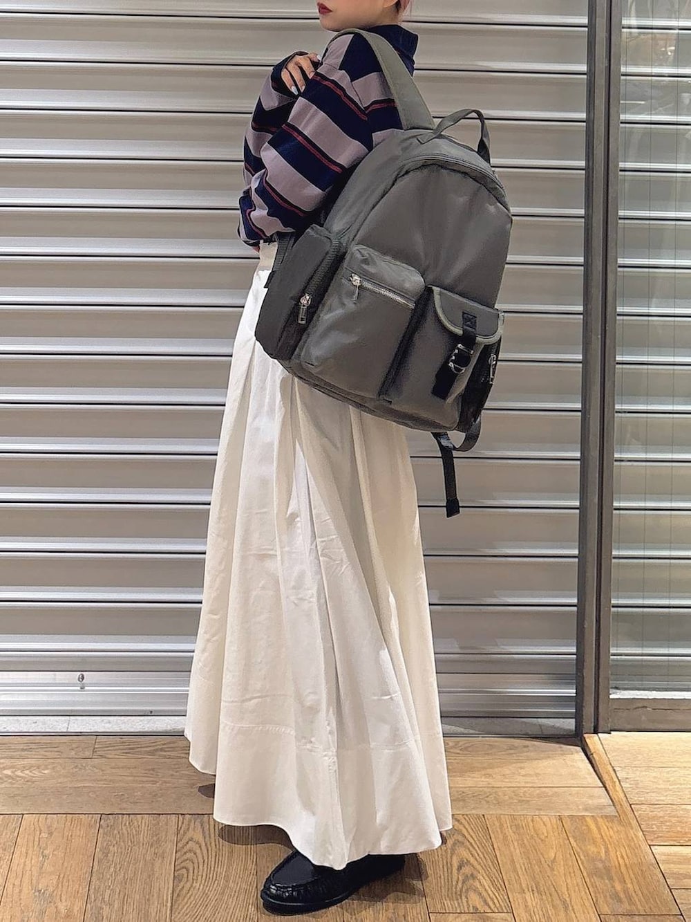 グリーン系のバックパック/リュック、ホワイト系のスカート、ブラック系のローファーを着用したレディースの冬コーディネートの3枚目の写真