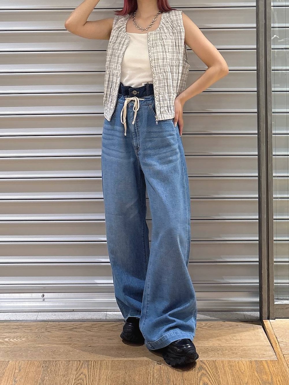 ブルー系のデニムパンツ、ホワイト系のベスト、ブラック系のローファーを着用したレディースの夏コーディネートの2枚目の写真