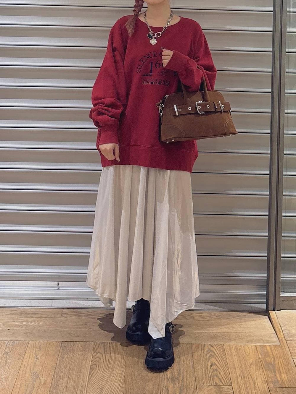 ブラック系のブーツ、ブラウン系のボストンバッグ、ホワイト系のスカートを着用したレディースの冬コーディネートの2枚目の写真