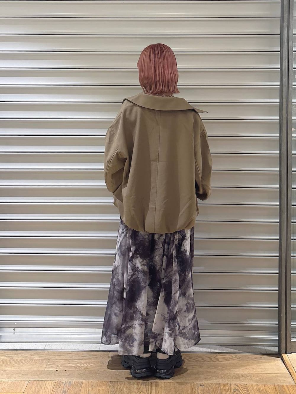 ブラウン系のブルゾン、グレー系のスカート、グレー系のサンダルを着用したレディースの春コーディネートの2枚目の写真