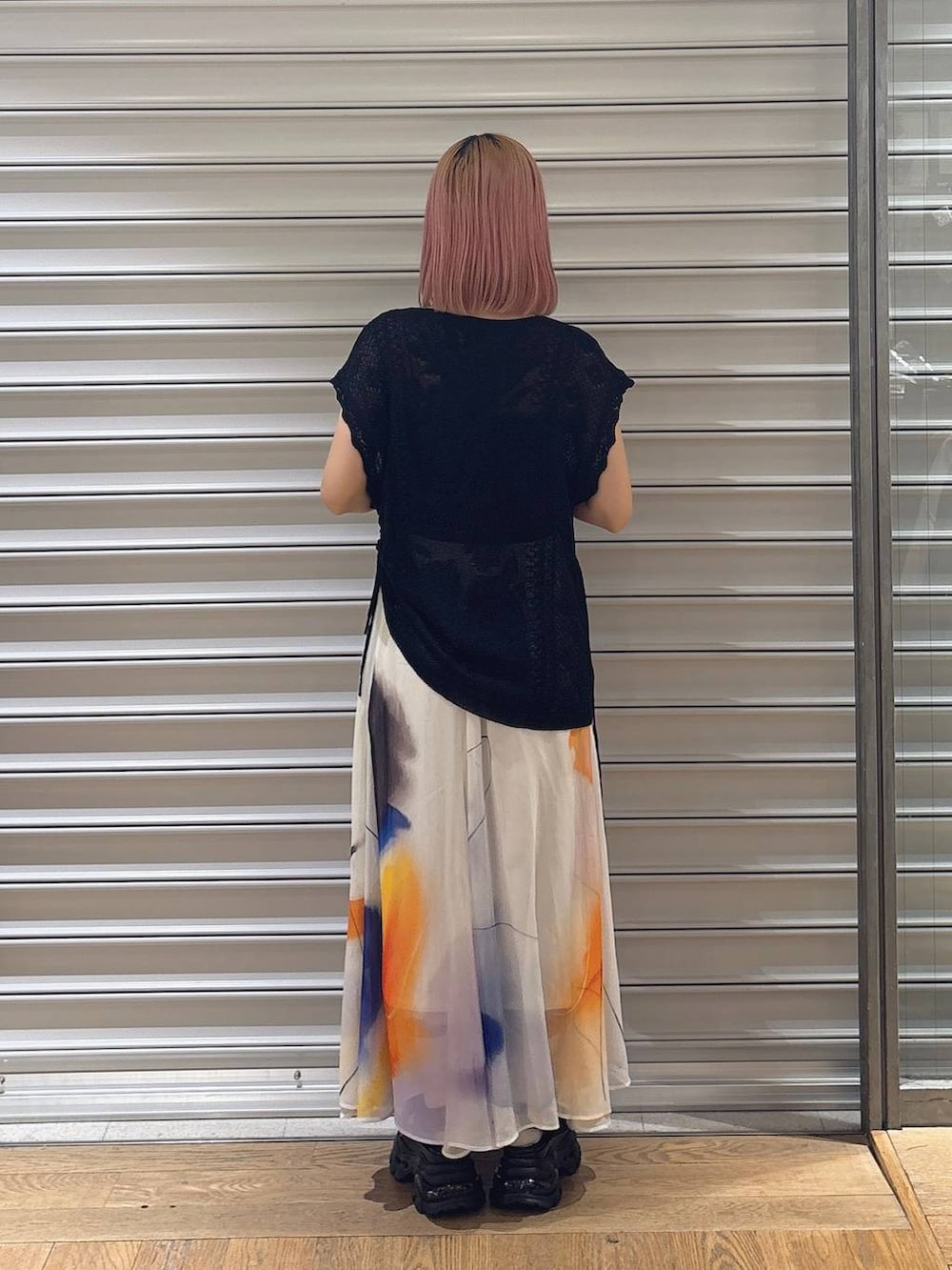 ホワイト系のスカート、ブラック系のサンダル、ブラック系のニット/セーターを着用したレディースの夏コーディネートの2枚目の写真