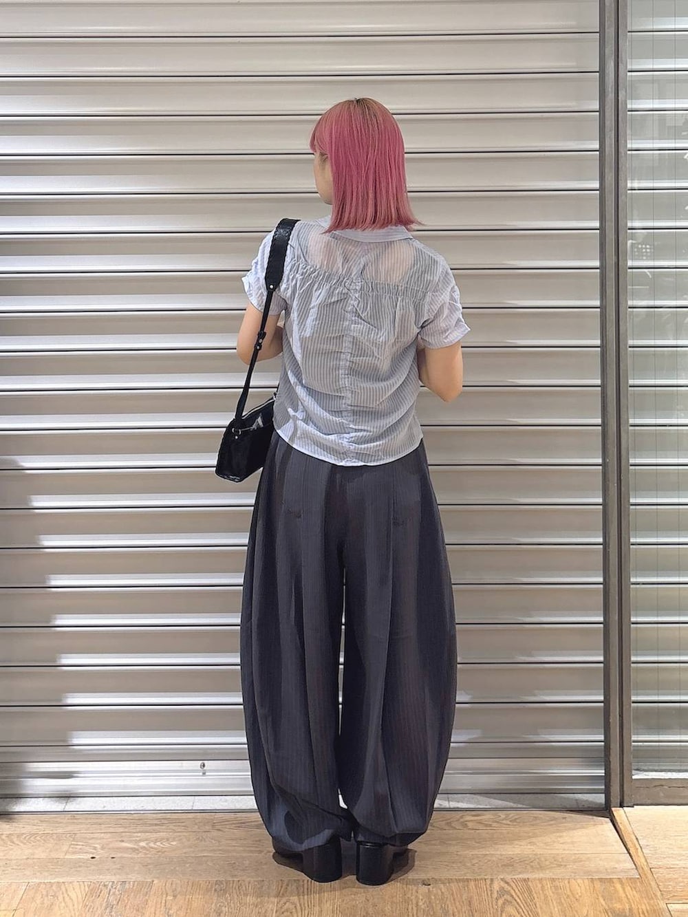 ブラック系のタンクトップ、グレー系のスラックス、ブラック系のショルダーバッグを着用したレディースの夏コーディネートの3枚目の写真