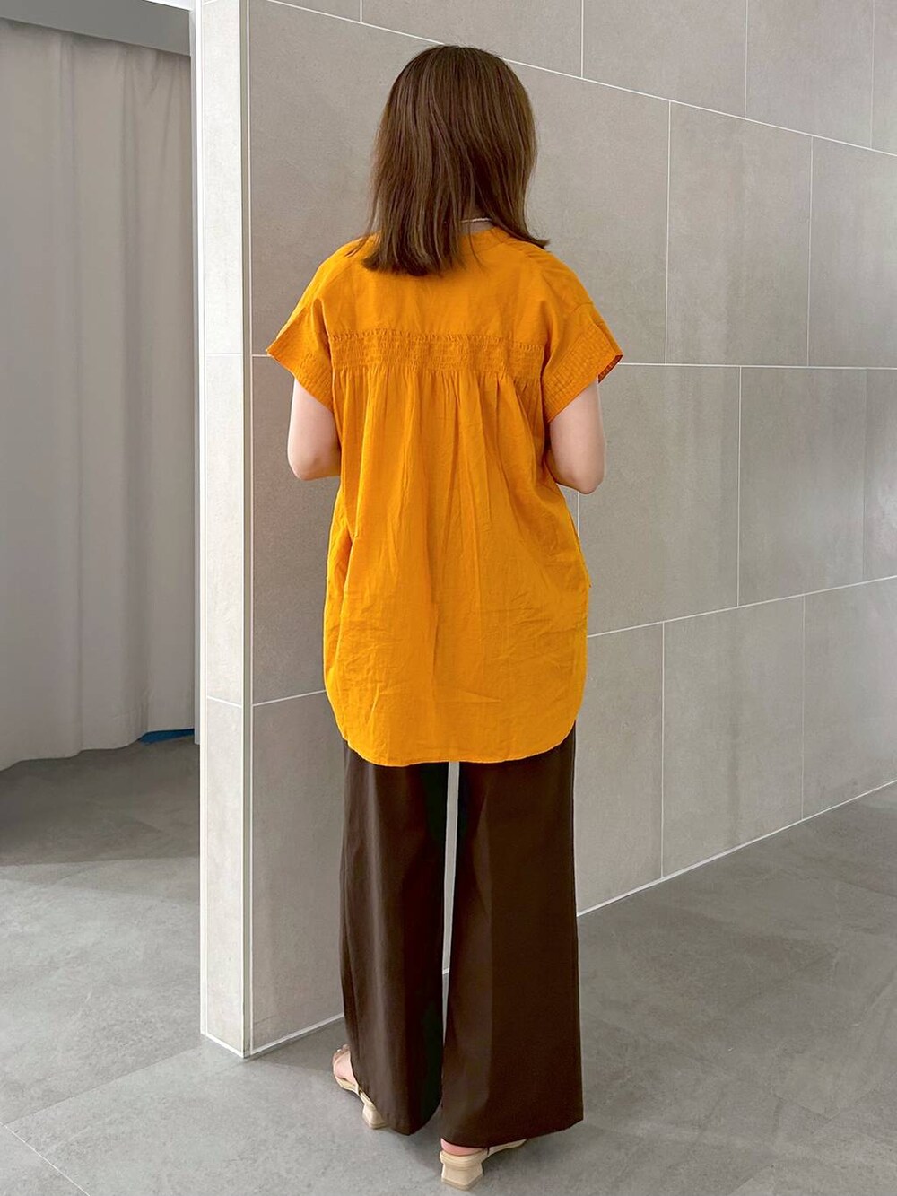 オレンジ系のシャツ/ブラウス、ブラウン系のその他パンツ、ベージュ系のサンダルを着用したレディースの夏コーディネートの8枚目の写真