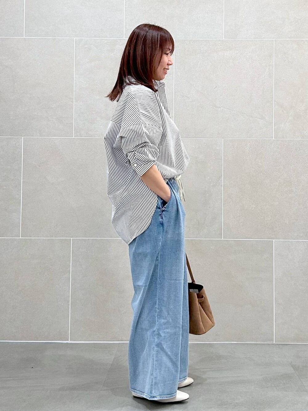 ホワイト系のパンプス、ブルー系のデニムパンツ、イエロー系のハンドバッグを着用したレディースの春コーディネートの6枚目の写真