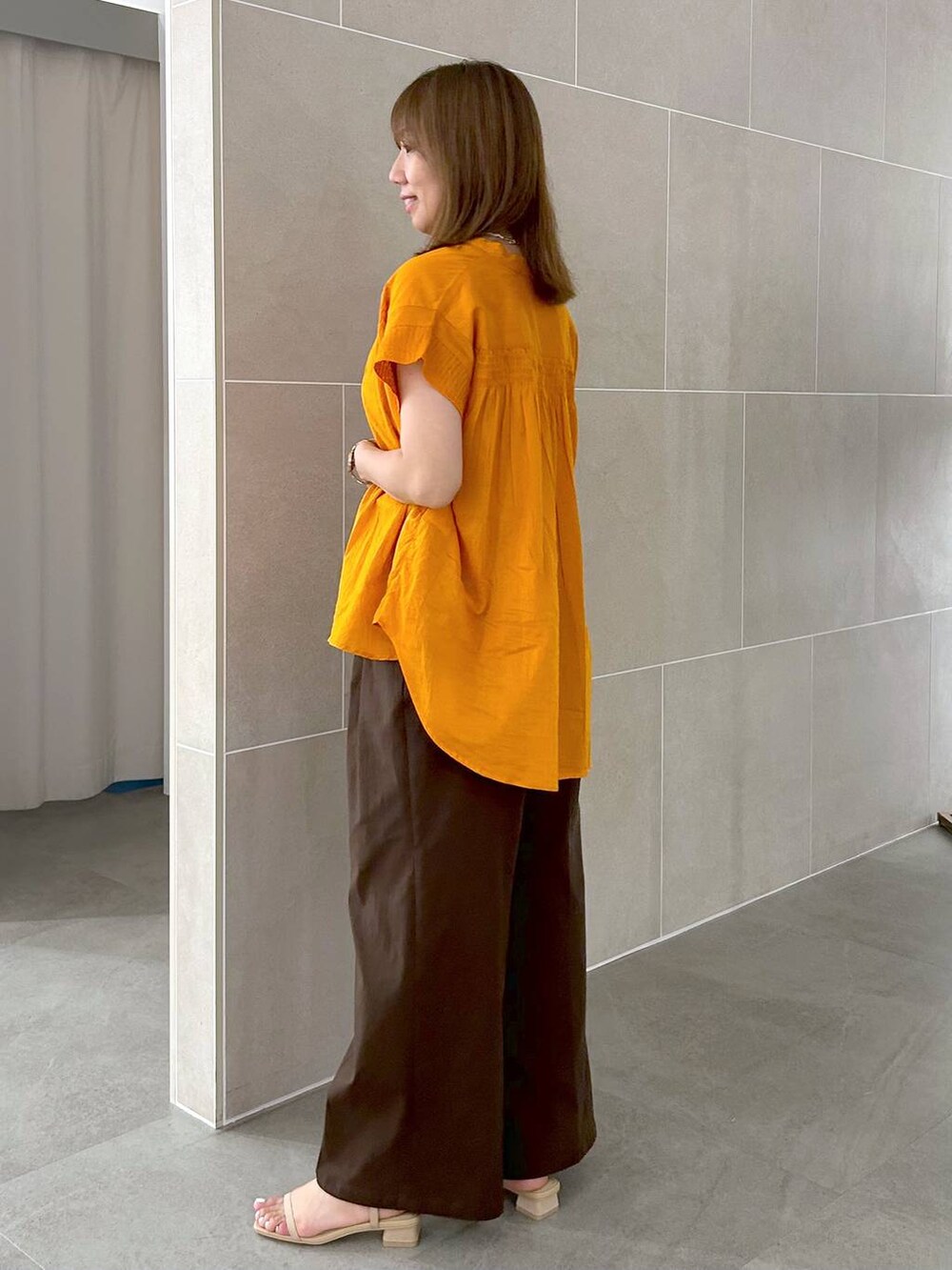 オレンジ系のシャツ/ブラウス、ブラウン系のその他パンツ、ベージュ系のサンダルを着用したレディースの夏コーディネートの7枚目の写真