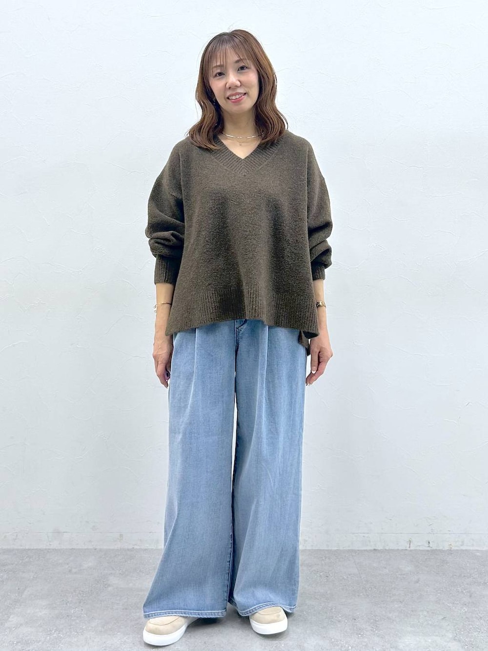 ベージュ系のハンドバッグ、ベージュ系のローファー、ブルー系のデニムパンツを着用したレディースの冬コーディネートの7枚目の写真