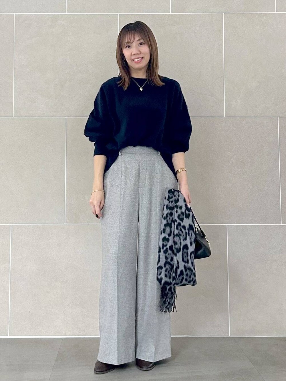 ブルー系のニット/セーター、グレー系のその他パンツ、ブラック系のストール/ショールを着用したレディースの秋コーディネートの2枚目の写真