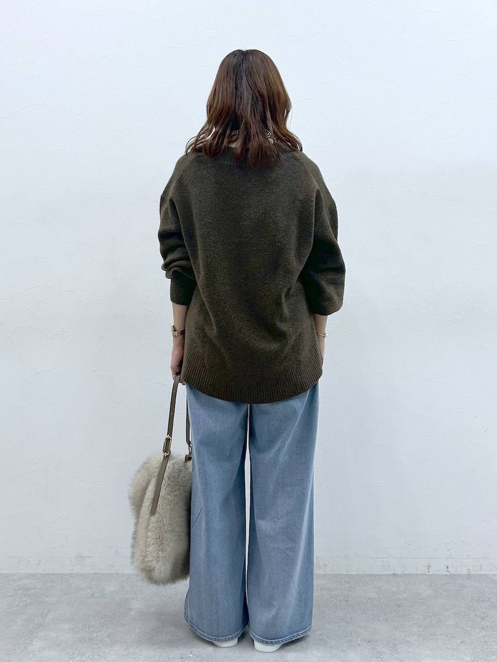 ベージュ系のハンドバッグ、ベージュ系のローファー、ブルー系のデニムパンツを着用したレディースの冬コーディネートの4枚目の写真