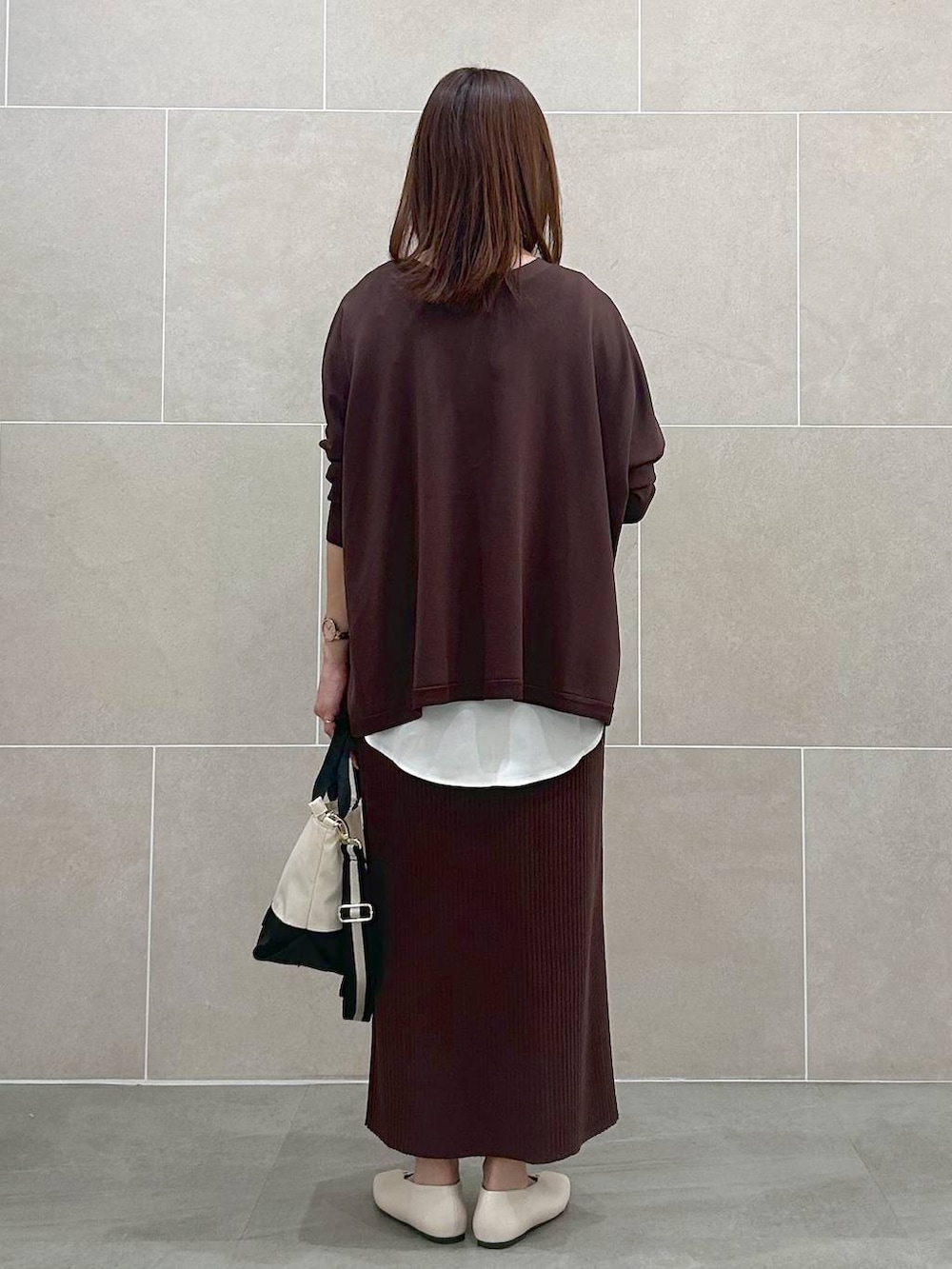 ホワイト系のパンプス、ブラウン系のスカート、ベージュ系のショルダーバッグを着用したレディースの春コーディネートの4枚目の写真