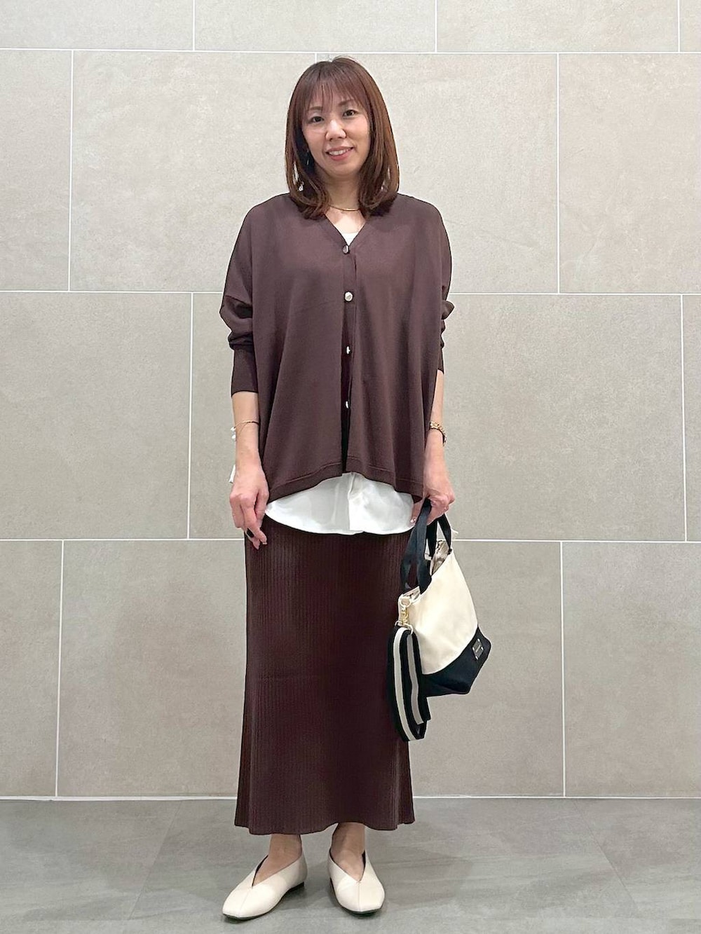 ホワイト系のパンプス、ブラウン系のスカート、ベージュ系のショルダーバッグを着用したレディースの春コーディネートの6枚目の写真