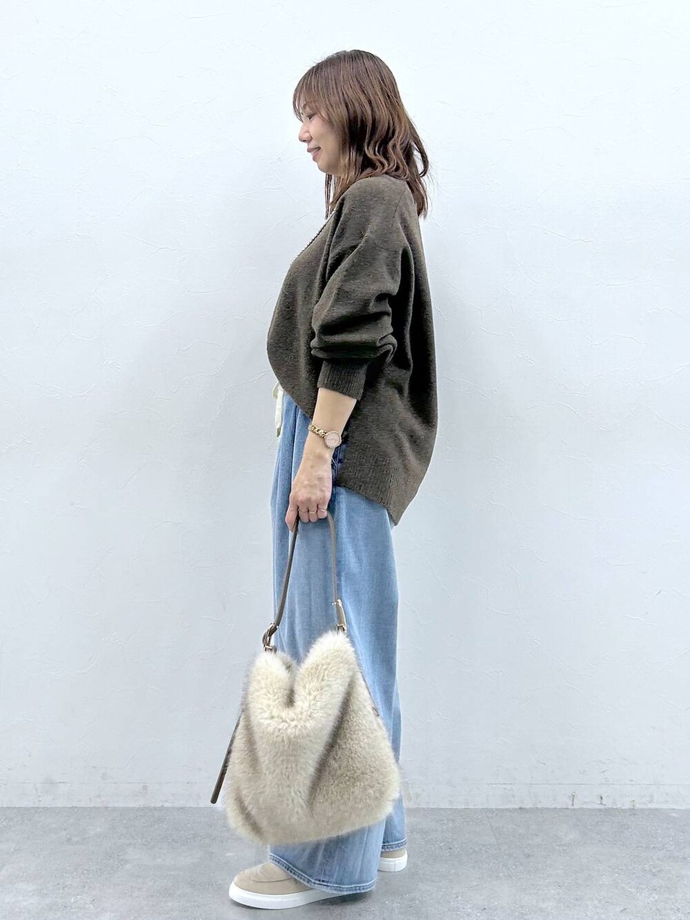 ベージュ系のハンドバッグ、ベージュ系のローファー、ブルー系のデニムパンツを着用したレディースの冬コーディネートの3枚目の写真