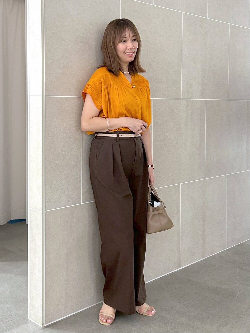 オレンジ系のシャツ/ブラウス、ブラウン系のその他パンツ、ベージュ系のサンダルを着用したレディースの夏コーディネートの5枚目の写真