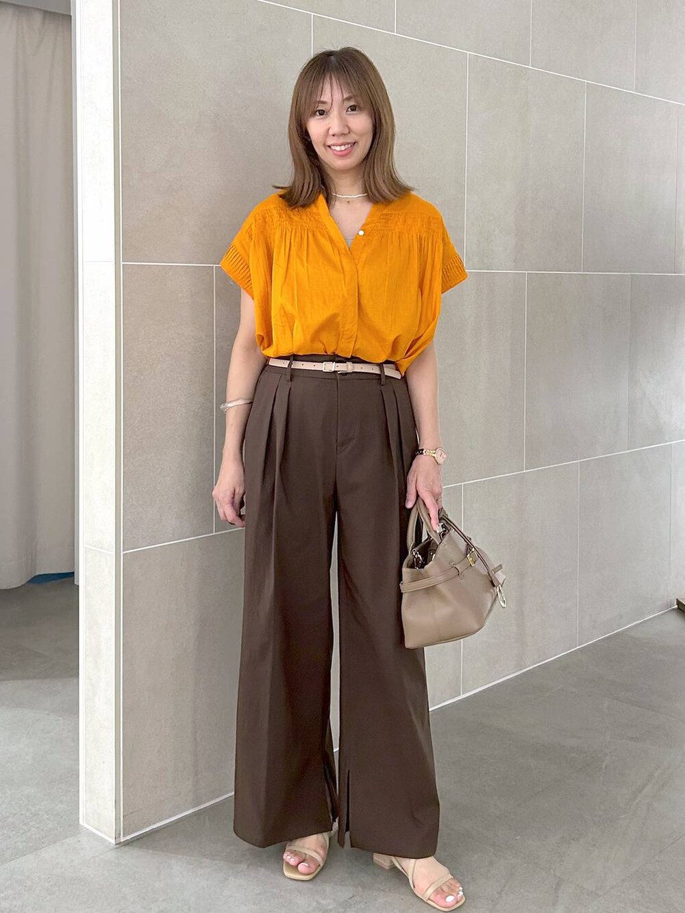 オレンジ系のシャツ/ブラウス、ブラウン系のその他パンツ、ベージュ系のサンダルを着用したレディースの夏コーディネートの2枚目の写真