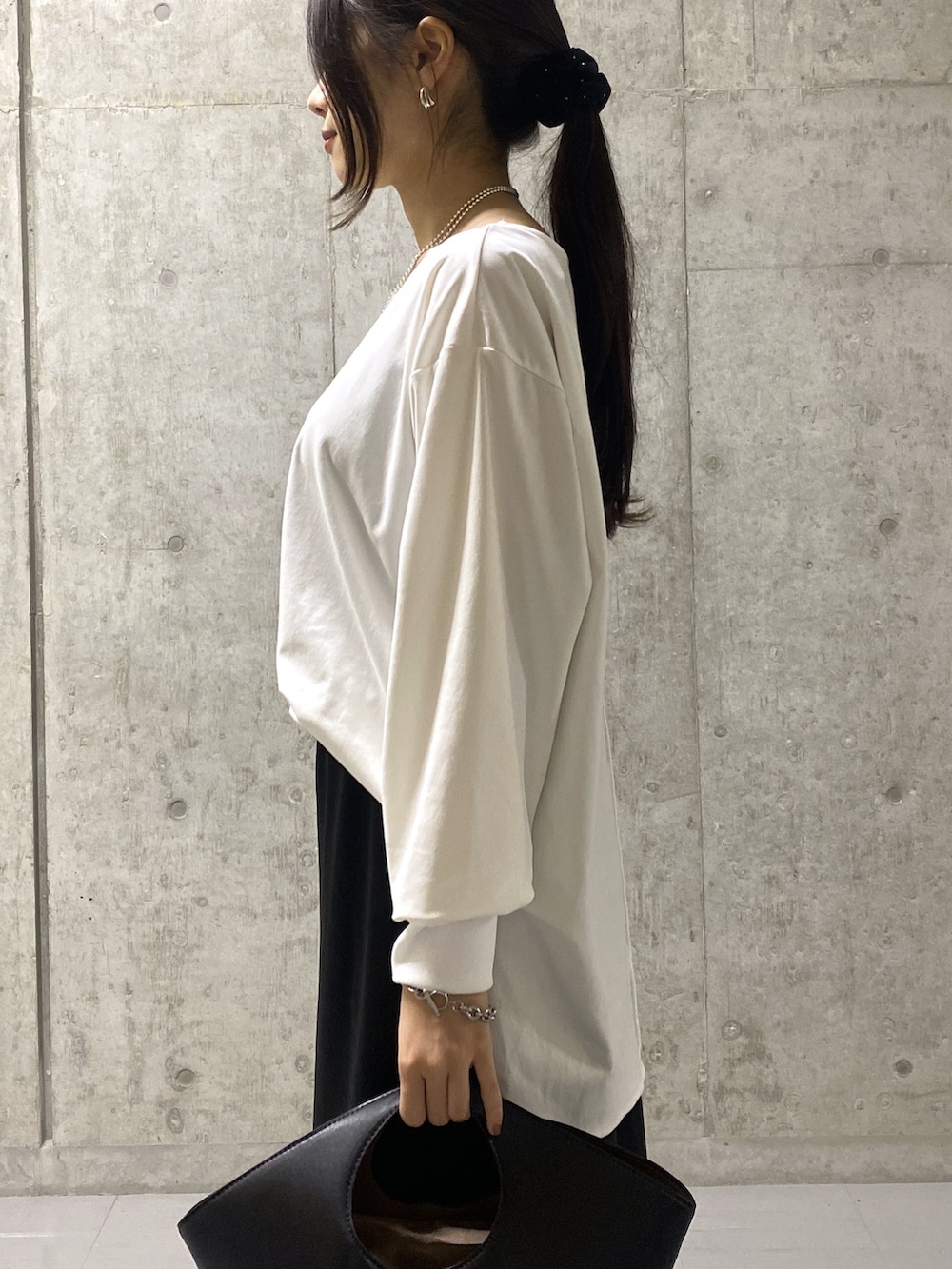 ブラック系のスカート、ホワイト系のTシャツ/カットソー、ブラック系のハンドバッグを着用したレディースの秋コーディネートの5枚目の写真