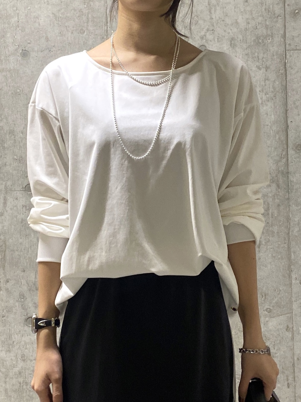 ブラック系のスカート、ホワイト系のTシャツ/カットソー、ブラック系のハンドバッグを着用したレディースの秋コーディネートの4枚目の写真