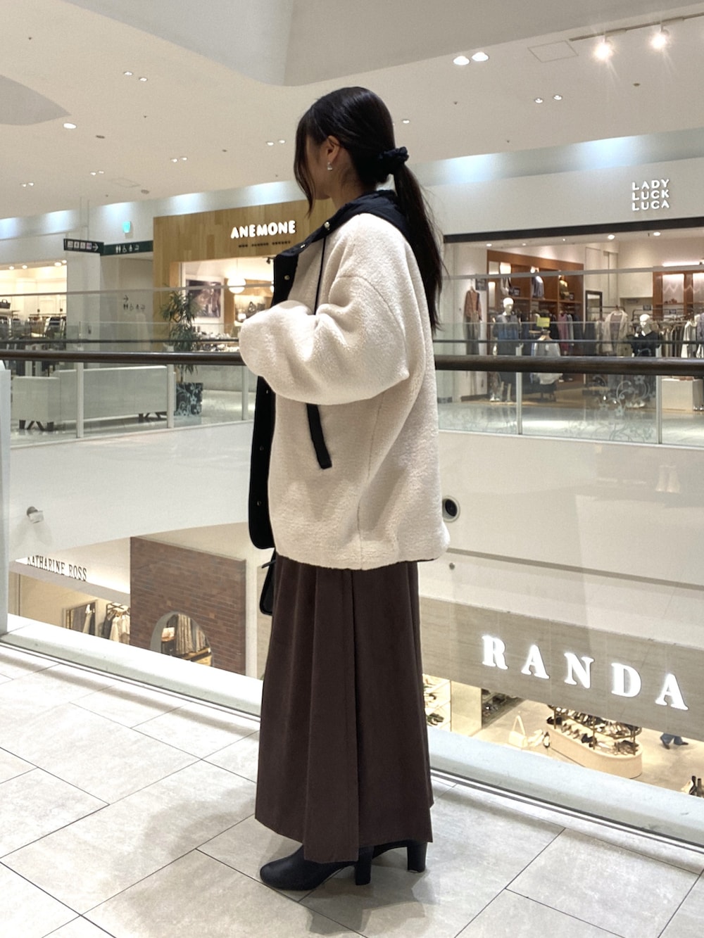 ホワイト系のその他アウター、ブラウン系のスカート、ブラック系のボストンバッグを着用したレディースの秋コーディネートの2枚目の写真