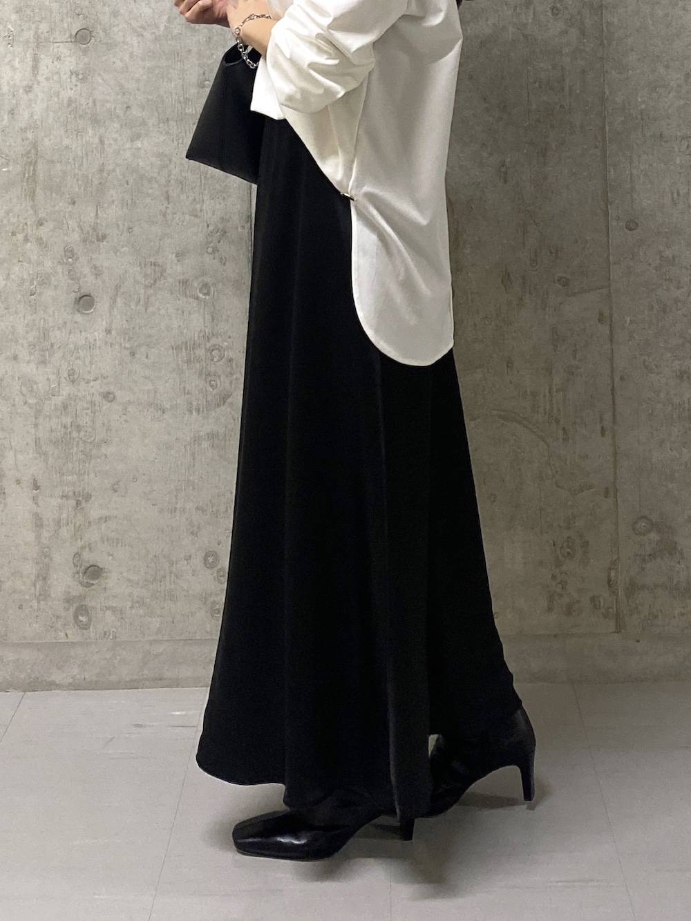 ブラック系のスカート、ホワイト系のTシャツ/カットソー、ブラック系のハンドバッグを着用したレディースの秋コーディネートの8枚目の写真