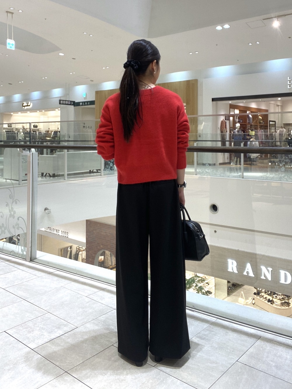 レッド系のカーディガン/ボレロ、ブラック系のスラックス、ブラック系のボストンバッグを着用したレディースの秋コーディネートの3枚目の写真