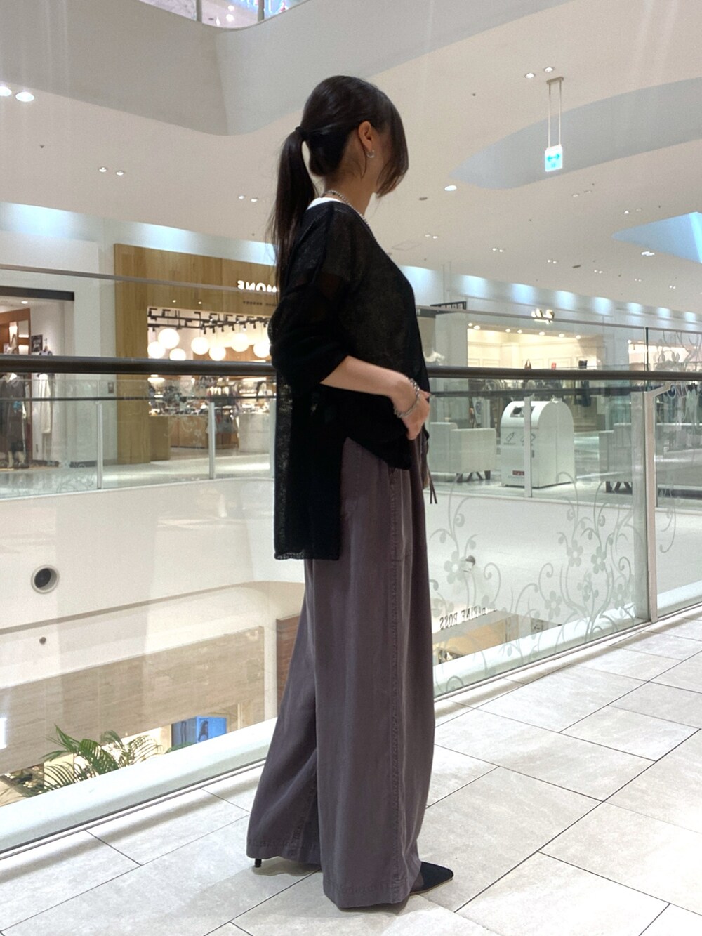 ブラック系のニット/セーター、ホワイト系のTシャツ/カットソー、ブラウン系のハンドバッグを着用したレディースの夏コーディネートの2枚目の写真