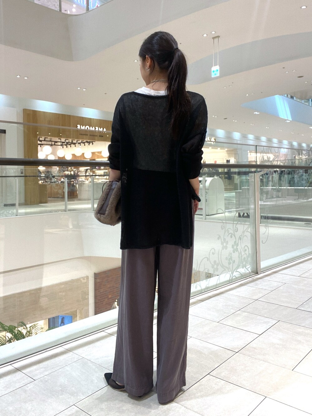 ブラック系のニット/セーター、ホワイト系のTシャツ/カットソー、ブラウン系のハンドバッグを着用したレディースの夏コーディネートの3枚目の写真