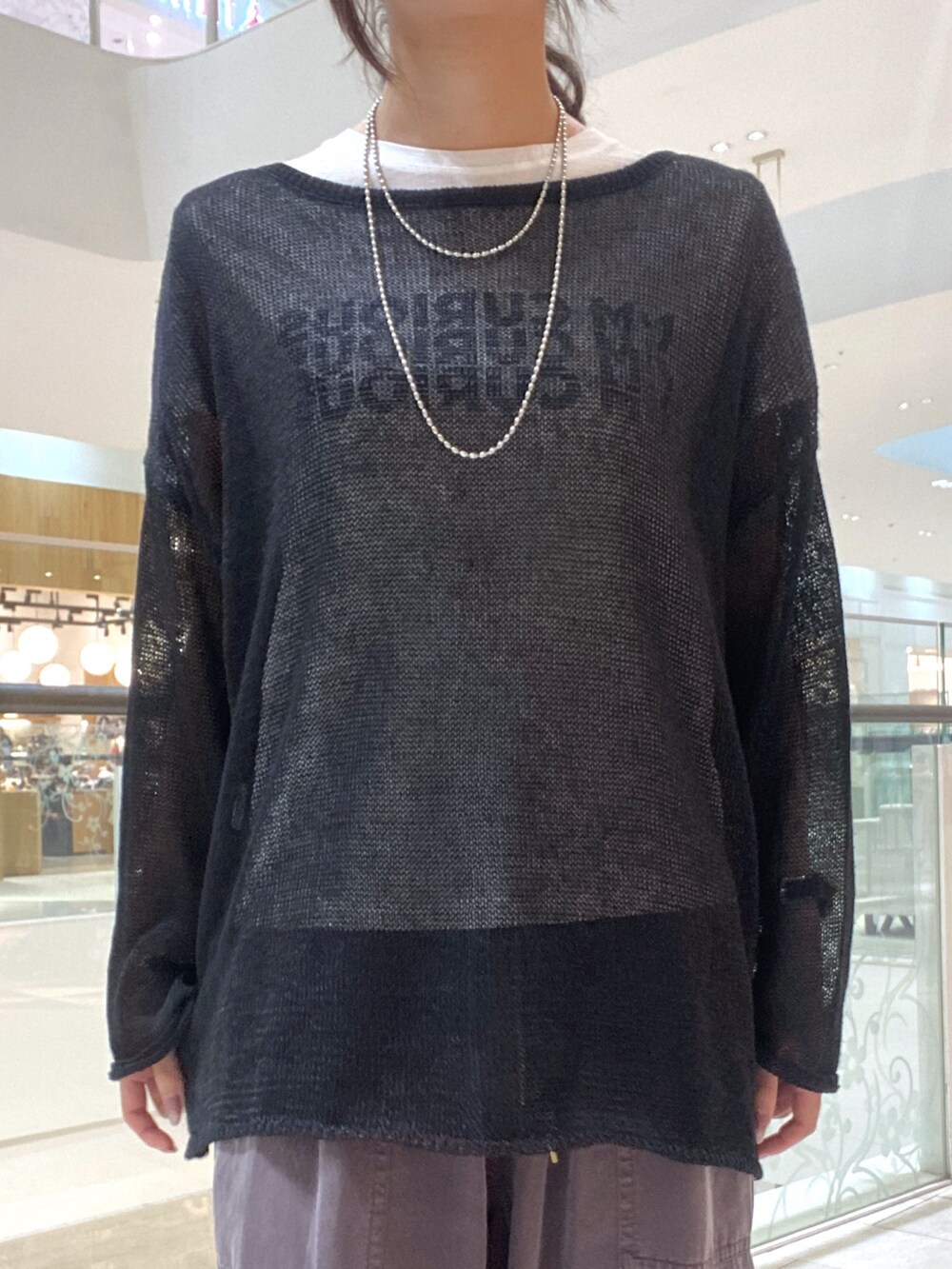 ブラック系のニット/セーター、ホワイト系のTシャツ/カットソー、ブラウン系のハンドバッグを着用したレディースの夏コーディネートの4枚目の写真