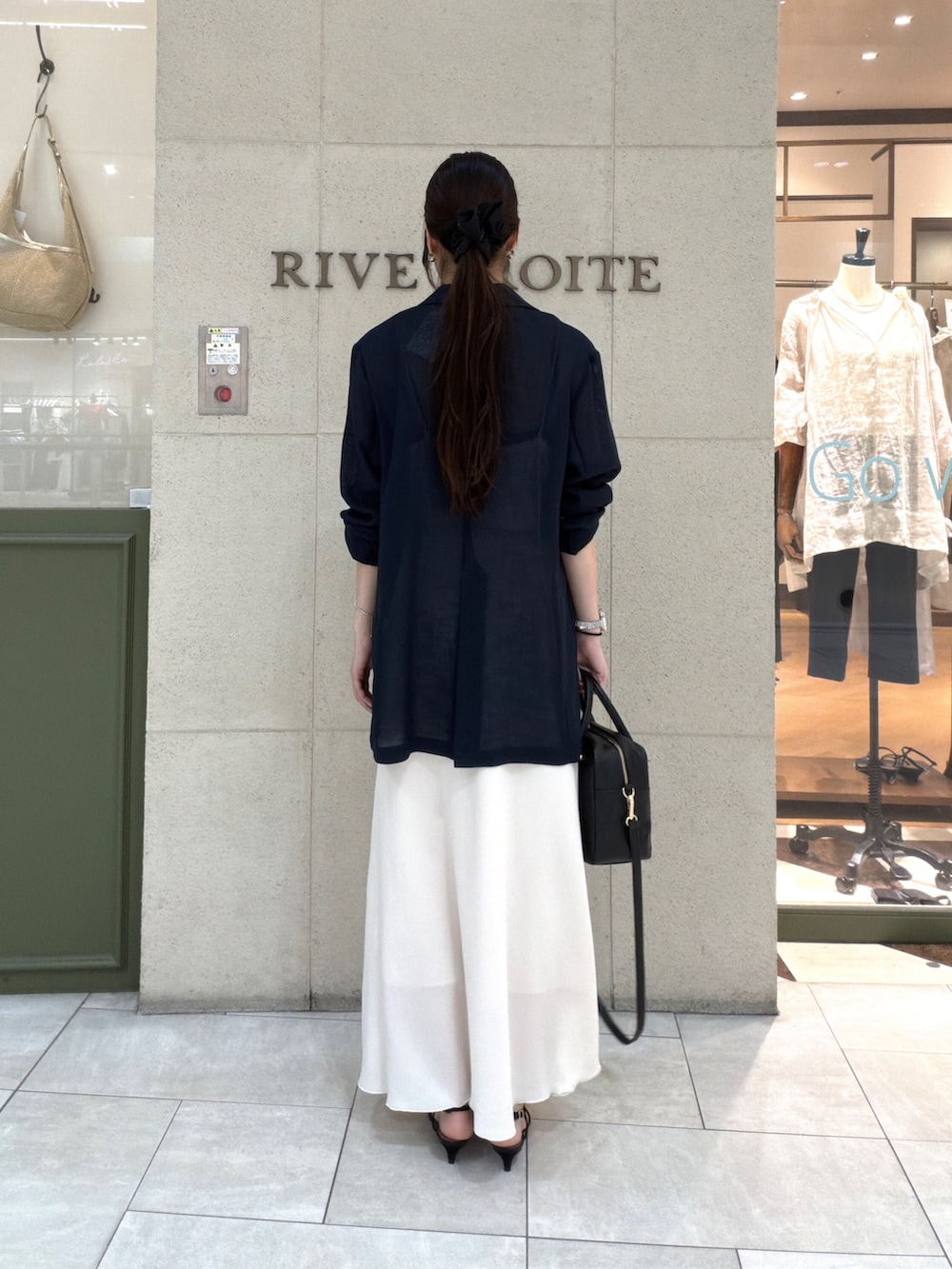 ブラック系のボストンバッグ、ホワイト系のスカート、ブラック系のサンダルを着用したレディースの夏コーディネートの3枚目の写真