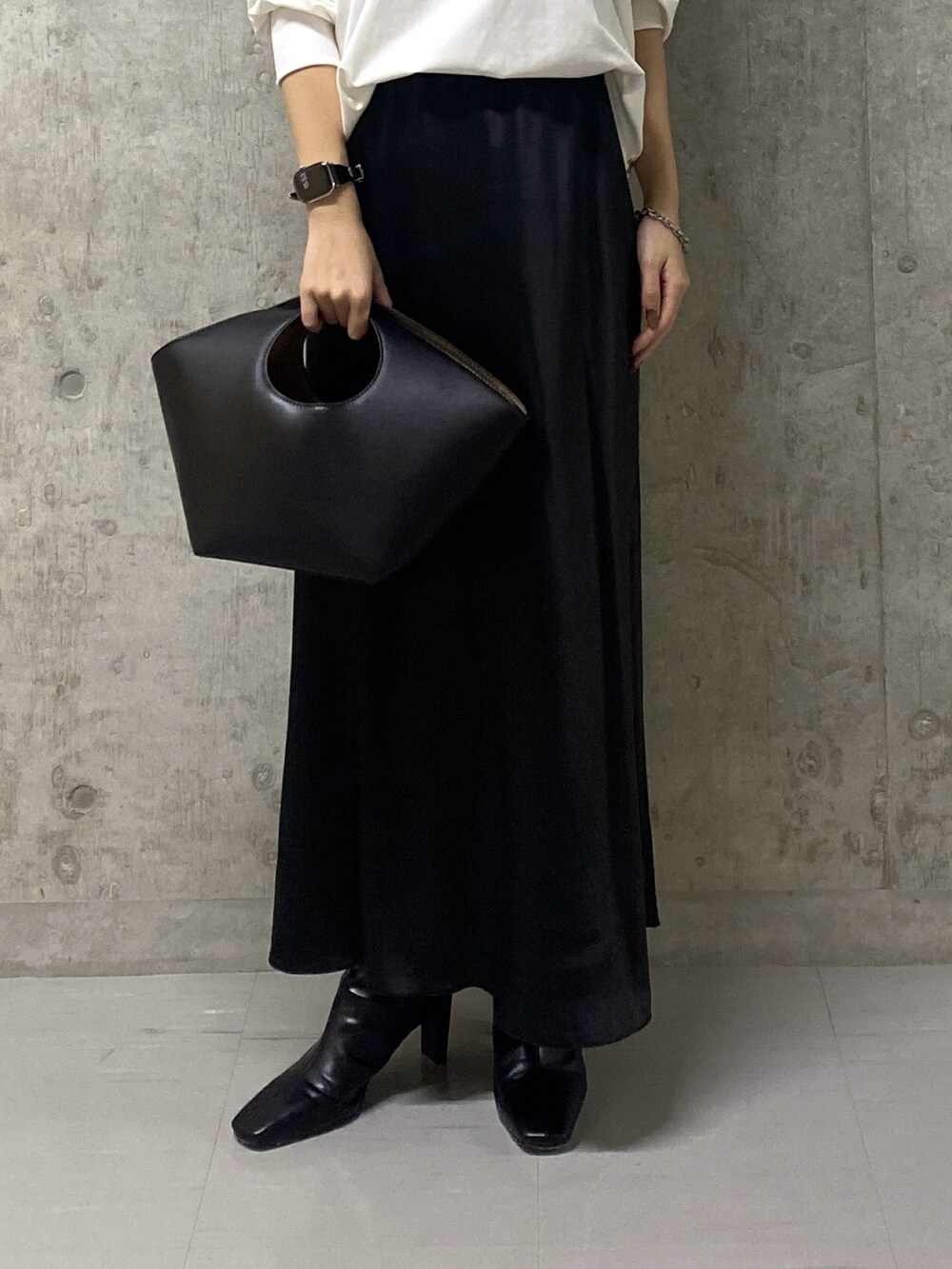 ブラック系のスカート、ホワイト系のTシャツ/カットソー、ブラック系のハンドバッグを着用したレディースの秋コーディネートの7枚目の写真