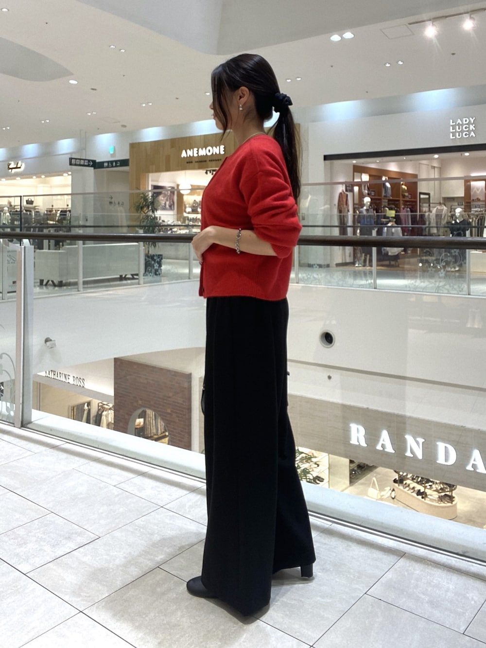 レッド系のカーディガン/ボレロ、ブラック系のスラックス、ブラック系のボストンバッグを着用したレディースの秋コーディネートの2枚目の写真