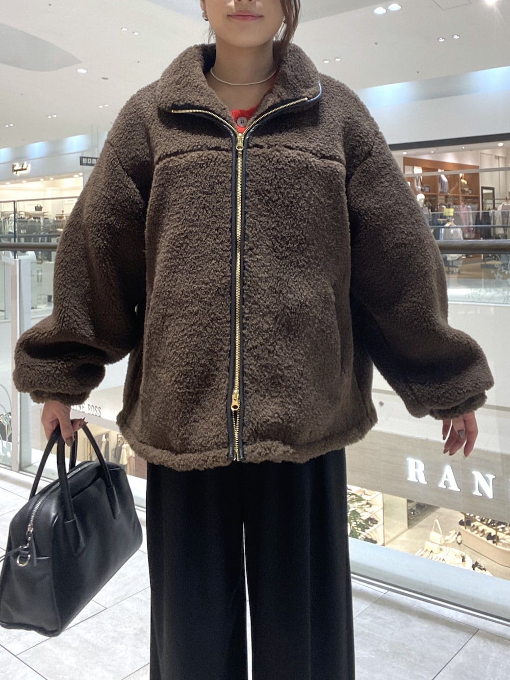 ブラウン系のその他アウター、ブラック系のスラックス、ブラック系のブーツを着用したレディースの秋コーディネートの4枚目の写真