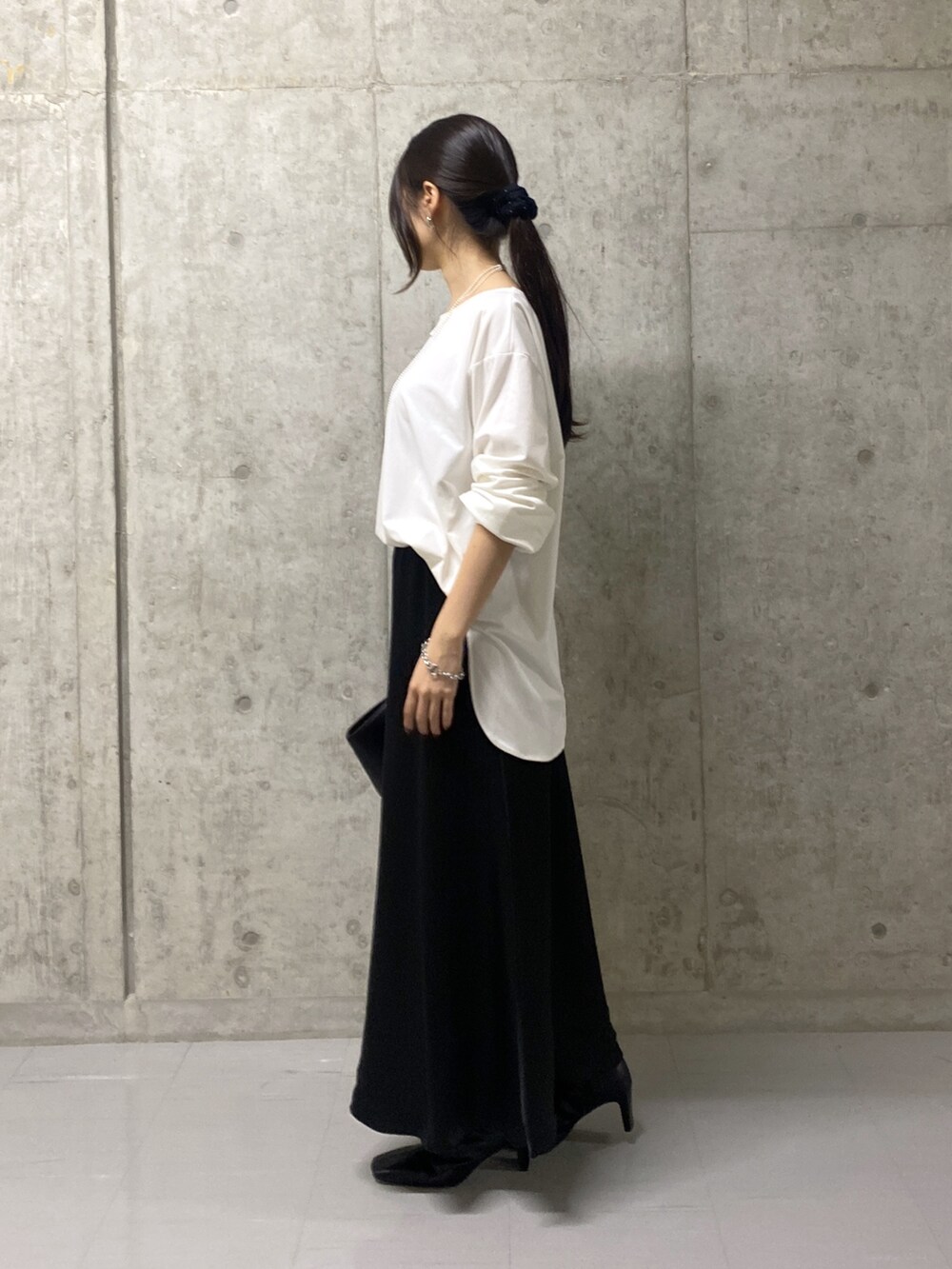 ブラック系のスカート、ホワイト系のTシャツ/カットソー、ブラック系のハンドバッグを着用したレディースの秋コーディネートの2枚目の写真